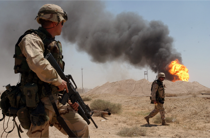 A U.S. soldier stands guard duty near a burning oil wel